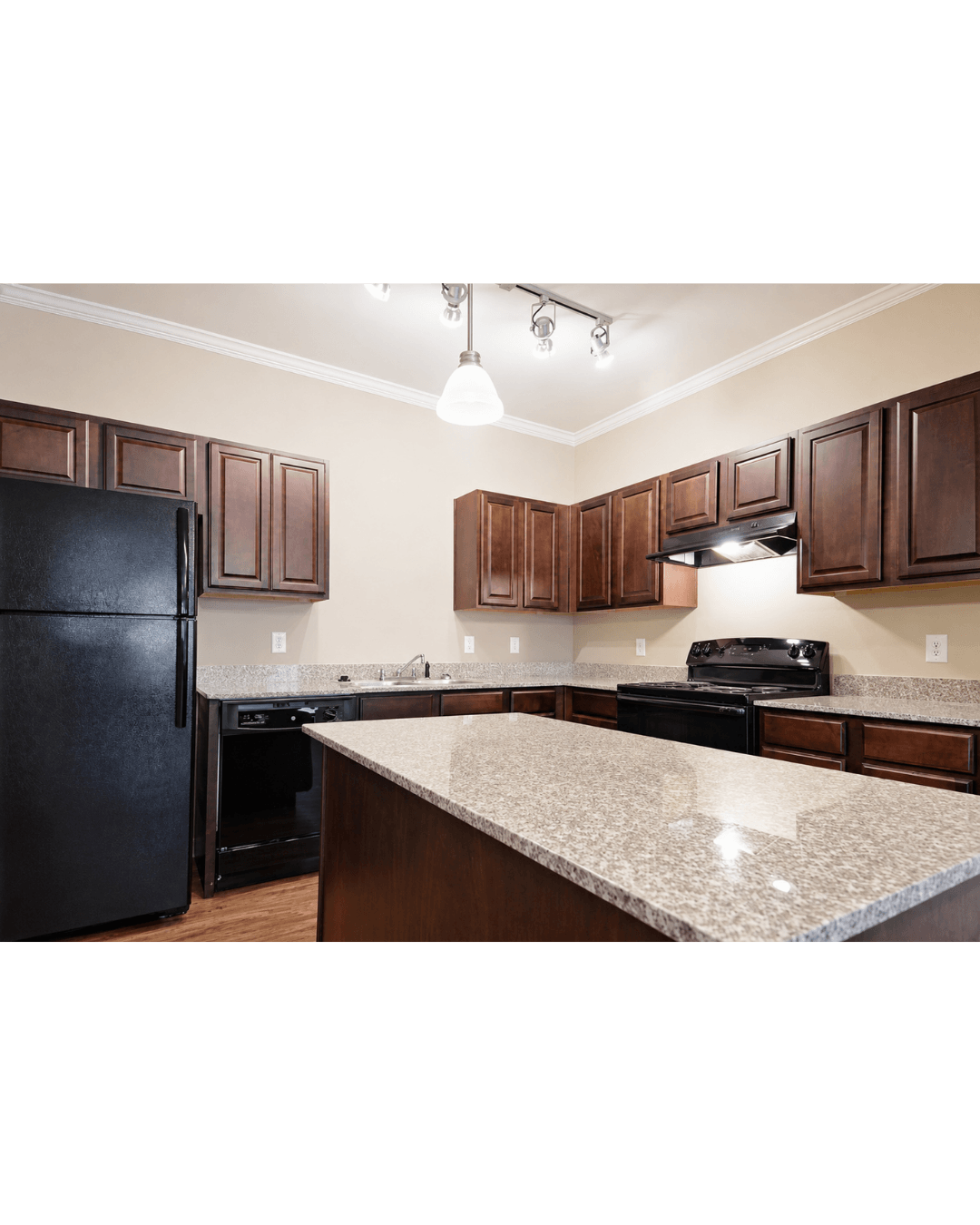 A kitchen with dark brown cabinets and a granite countertop.